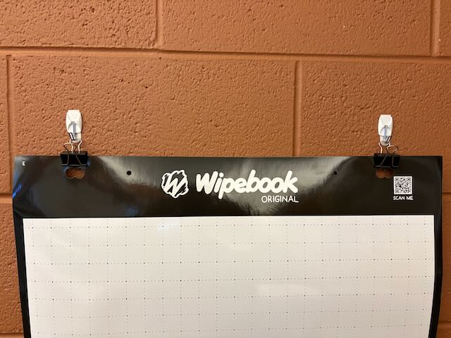 A Wipebook hanging from two binder clips on command hooks